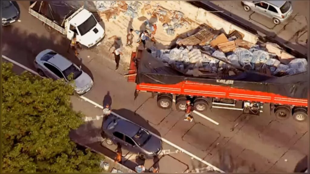 Carreta com carga de arroz tomba, e, enquanto os bombeiros socorrem o caminhoneiro, a carga é saqueada