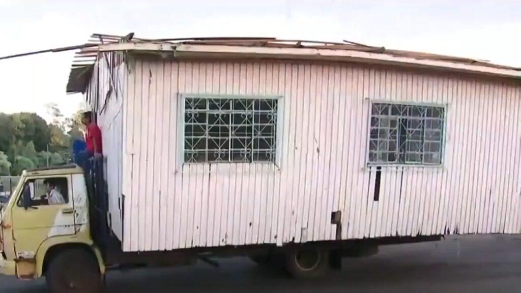 Caminhão transporta casa de madeira com homem no teto do veículo em Chapecó