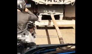 Motociclista se posiciona entre caminhão sendo puxado por cabão