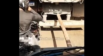 Motociclista se posiciona entre caminhão sendo puxado por cabão