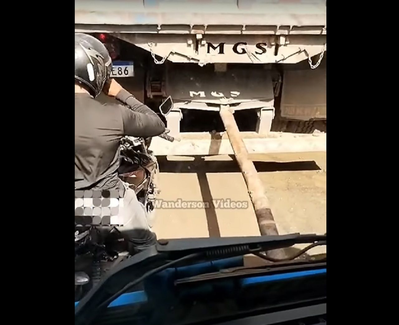 Motociclista se posiciona entre caminhão sendo puxado por cabão