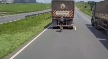 Ciclista se aproxima perigosamente da traseira de carreta em rodovia movimentada