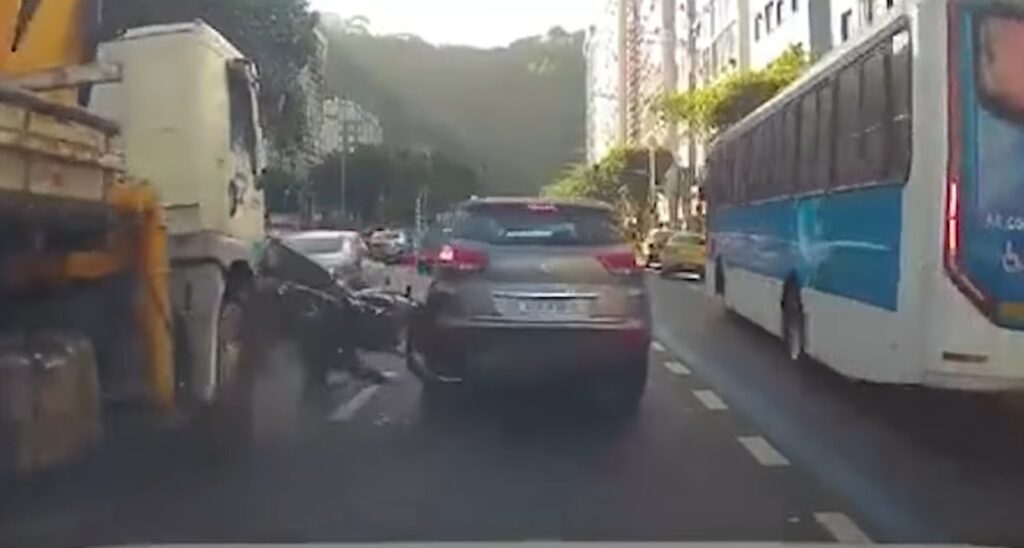 Motocicleta fica pendurada entre carro e caminhão em avenida