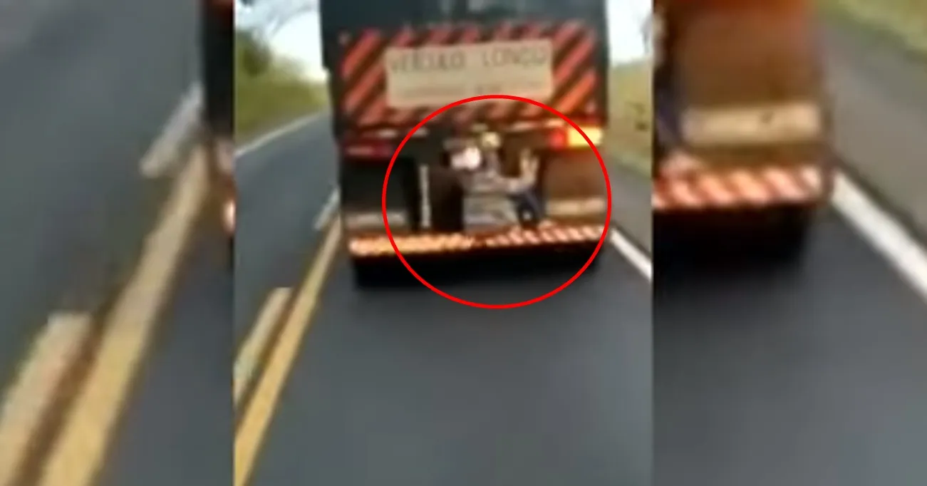 Homem se arrisca pegando carona em traseira de carreta em rodovia
